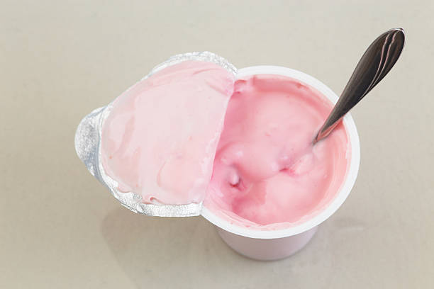 Yogurt Opened cup of fruit yogurt with spoon in it close up photography. Cup of Yogurt stock pictures, royalty-free photos & images