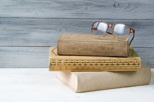 istock Stack of old books and reading glasses on wooden background 519897006