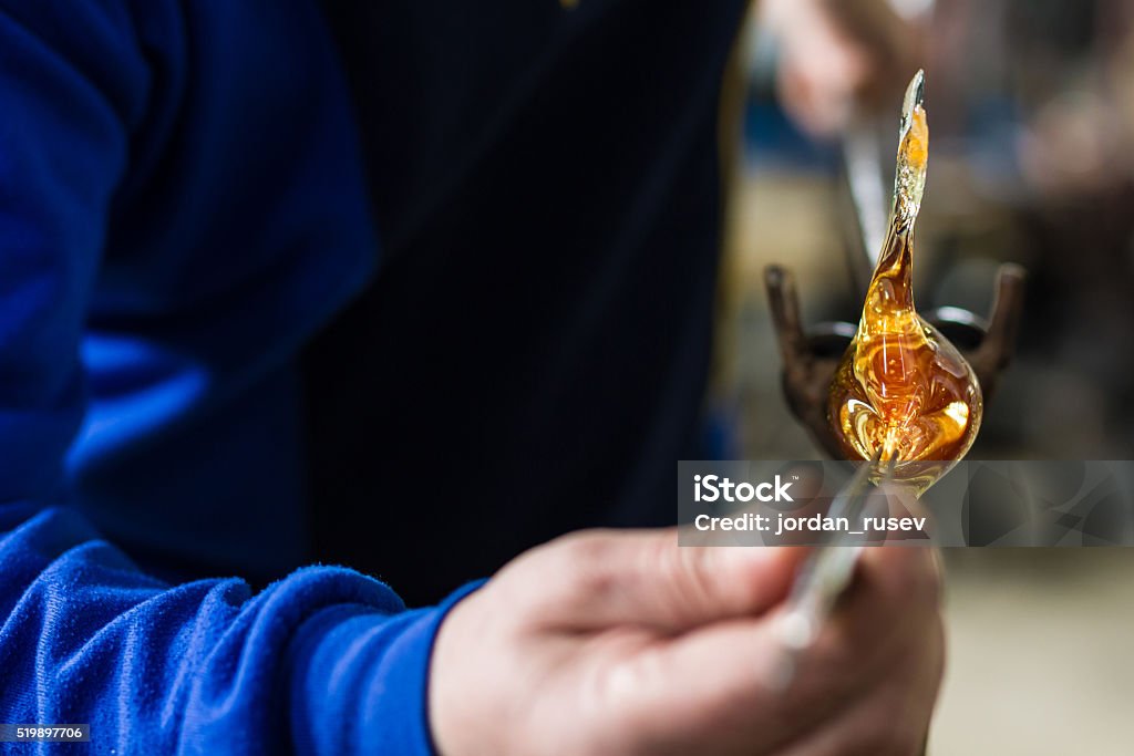 Glass crafting worker make glass souvenir Glass blower forming beautiful piece of glass. A glass crafter is burning and blowing an art piece. Art Stock Photo