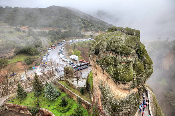 Meteora, Greece - March 13, 2016: The monastery complex of Meteora. Parking tourist and tour buses in front of the rock monostyr in rainy weather