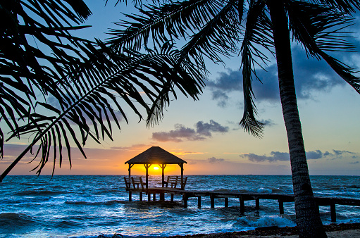 A palapa at sunrise on the end of a pier in Placencia, Belize.