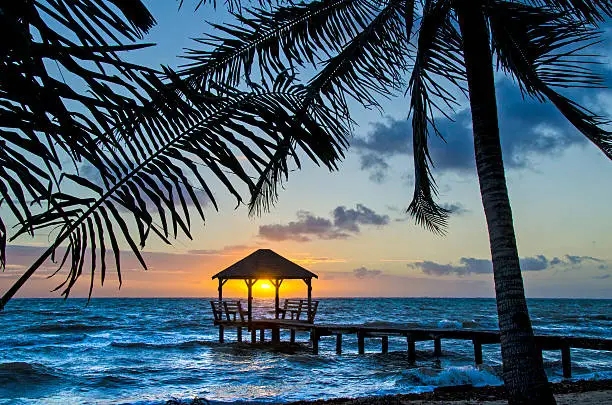 A palapa at sunrise on the end of a pier in Placencia, Belize.