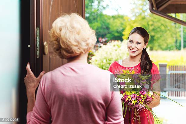 Young Woman Bringing Birthday Flowers To Her Grandmother Stock Photo - Download Image Now