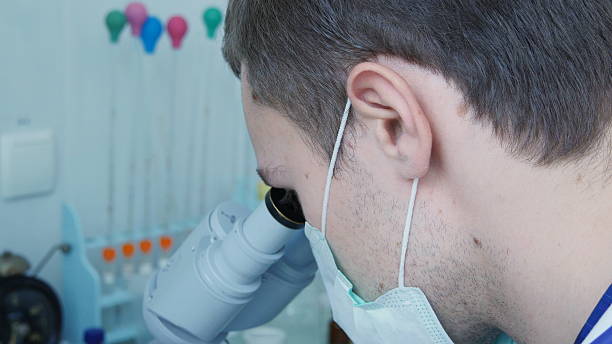 istock doctor looking through the eyepiece of a microscope. 519914250