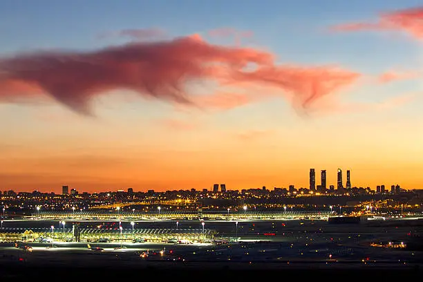 This is a view of Madrid from the Airport at sunset, with the lights of the city and the beautiful orange and blue cloudy sky.