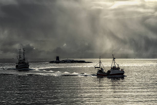 Dramatic light with two fishing boats Lofoten Islands, Norway, Marts 19, 2016 - Travel the Arctic North mann stock pictures, royalty-free photos & images