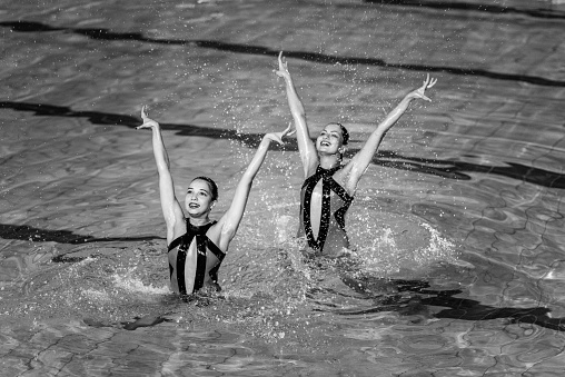 Synchronized swimming competition, duet performing. Black and white