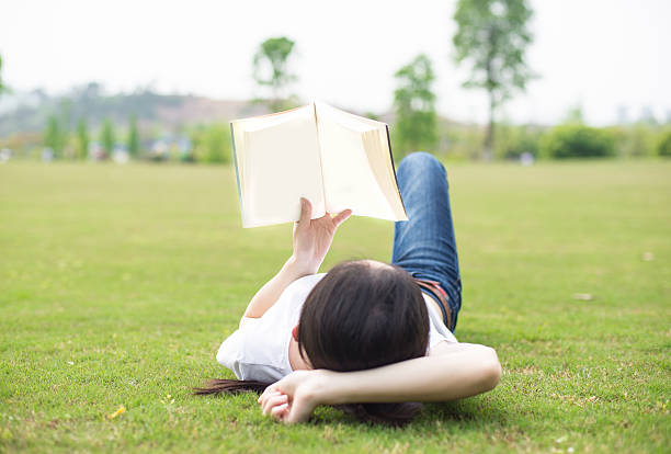 istock beautiful girl with book on the grass 519920738