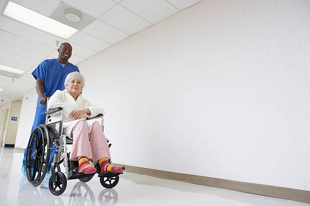 nurse pushing patient in a wheelchair - pushing women wall people imagens e fotografias de stock