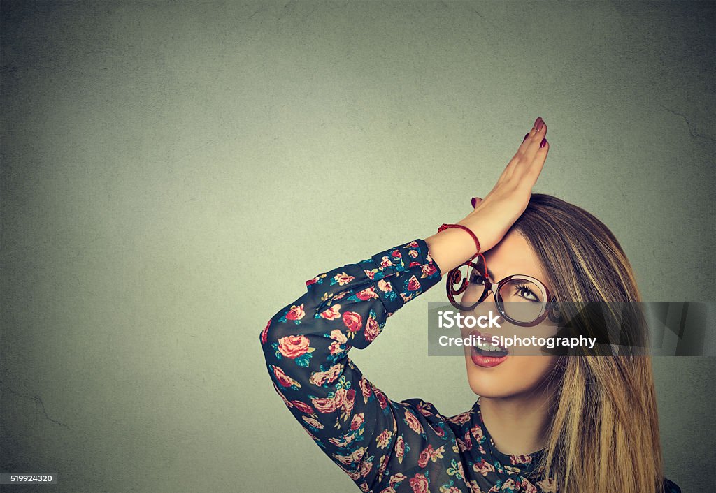 silly woman slapping hand on head having duh moment Regrets wrong doing. Closeup portrait silly young woman, slapping hand on head having duh moment isolated on gray background. Negative human emotion facial expression feeling, body language, reaction Mistake Stock Photo