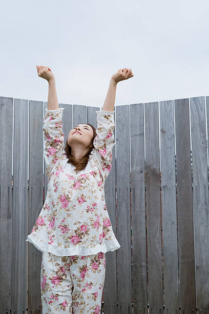 istock Asian woman in nightwear stretching outside 519925310