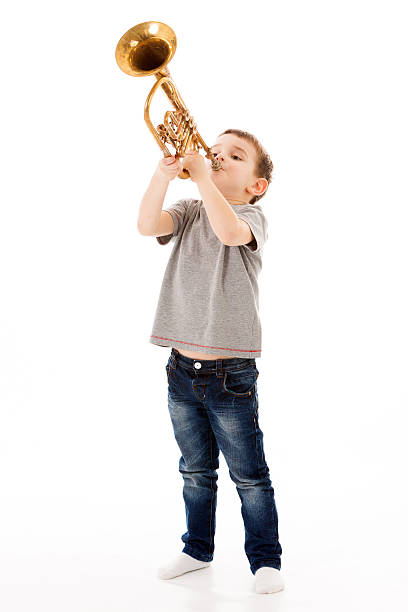 istock young boy blowing into a trumpet against white background 519927492