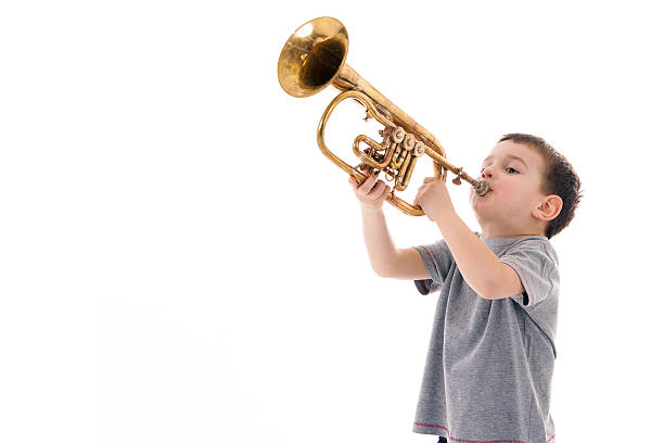 istock young boy blowing into a trumpet against white background 519927520
