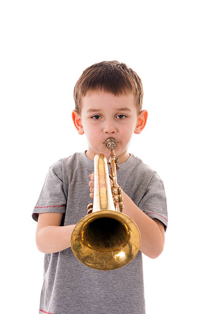 istock young boy blowing into a trumpet against white background 519927684