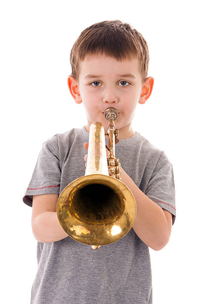 istock young boy blowing into a trumpet against white background 519927720