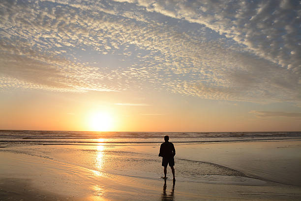 istock Man walking on the beach at sunrise. 519928346