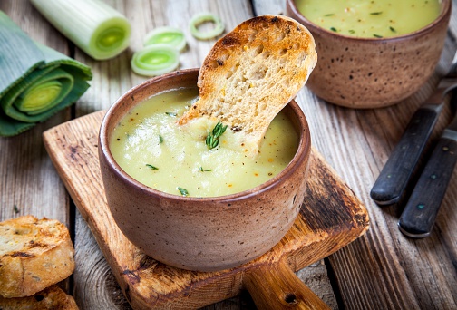 homemade cream of leek soup with croutons on wooden table