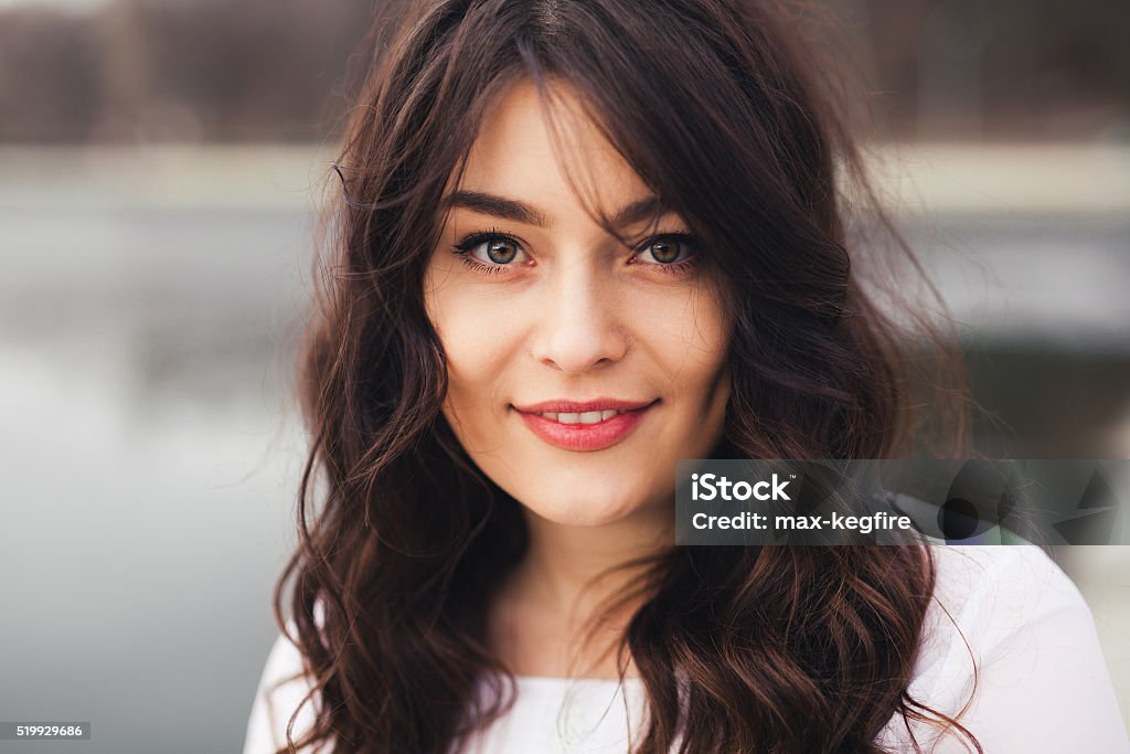 Beautiful woman face closeup Beautiful woman face closeup. Close up portrait of young woman with natural make up smiling and looking to camera outdoors. Adult Stock Photo