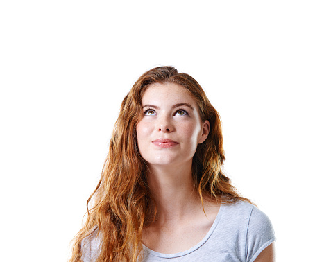 Studio shot of a beautiful young woman looking up at copyspace