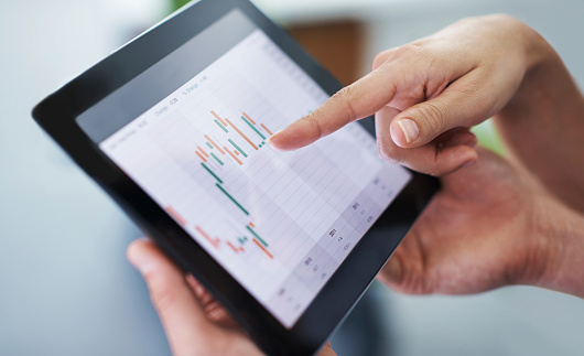 Shot of a businesswoman pointing at the screen of a digital tablet being held by her colleague