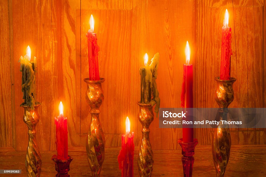 Lit green and red candles against antique wood door (P) Seven green and red candles are lined up and dripping with wax as they burn against an antique wooden door. Antique Stock Photo