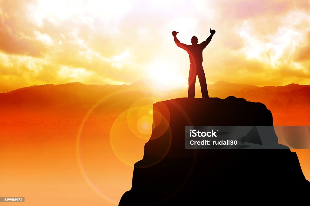 Success Silhouette of a male figure on top of a mountain Achievement Stock Photo