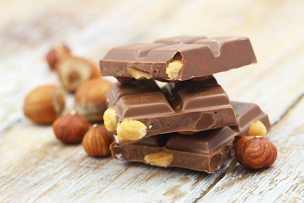 istock Milk chocolate pieces with whole hazelnuts on rustic wooden surface 519958108