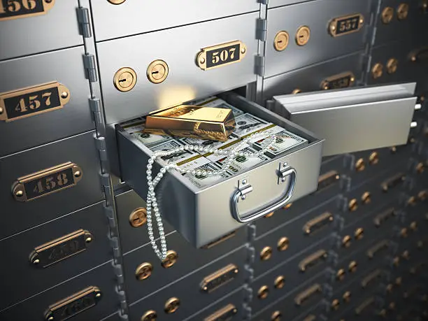 Photo of Open safe deposit box with money, jewels and golden ingot.