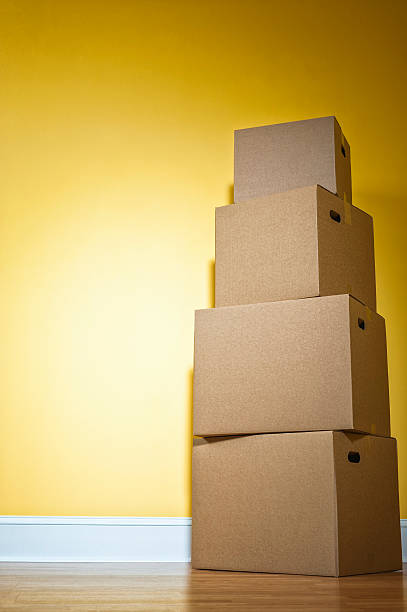 istock Stack of corrugated cardboard moving boxes against yellow wall 519961530