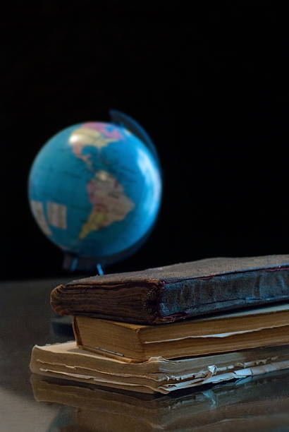 vieux livres et globe sur le bureau en noir d'ambiance - sphere library globe old fashioned photos et images de collection