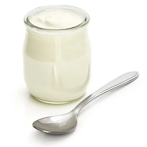 A jar of plain yogurt with a silver spoon. 