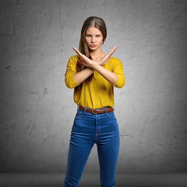 Serious young woman making X sign with her arms to stop doing something. Signs symbols, body language.