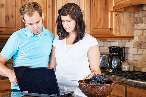 istock Young Couple in Kitchen Paying Bills Online 519975253
