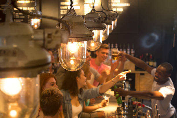 Friends at a Busy Bar Mixed group of people ordering drinks at the bar cocktail bar busy stock pictures, royalty-free photos & images