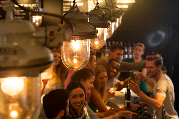 Friends at a Busy Bar Mixed group of people ordering drinks at the bar pub bar counter bar men stock pictures, royalty-free photos & images