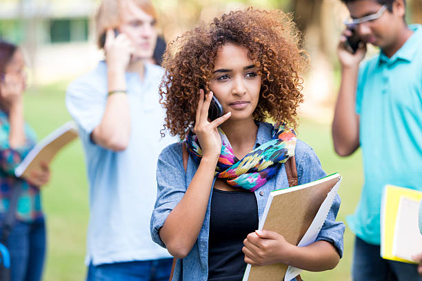 istock Beautiful African American college student using cell phone outdoors 519978605