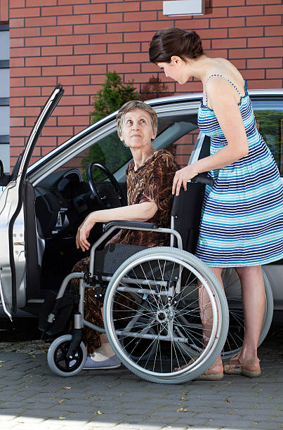 Senior female driver on wheelchair Senior female driver on wheelchair and young woman senior adult car nurse physical impairment stock pictures, royalty-free photos & images