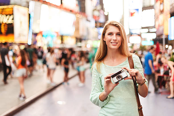 istock pretty woman smiling on times square with camera 519999625