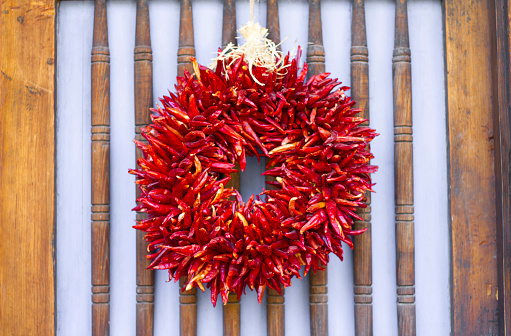 A round red chili pepper ristra hangs on a traditional wood door in Santa Fe, NM. (A ristra hung on a NM door is not only decorative but protects against evil spirits according to traditional beliefs).