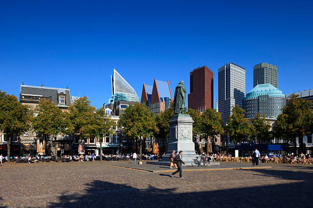 The Hague, Netherlands - September 3, 2014: pedestrians on Plein in The Hague with the statue of Dutch King William of Orange (sculptor: Louis Royer; 1848) on the left and the modern office towers in the background