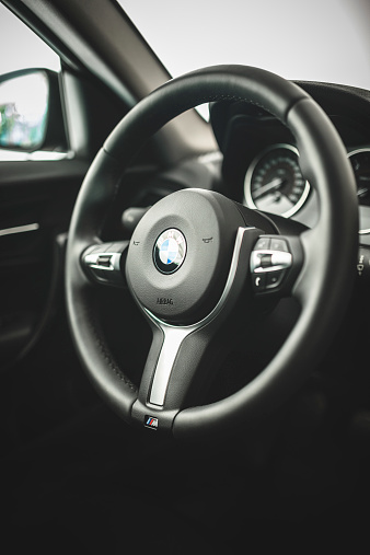 Florence, Italy - October 5, 2014: Interior view of the dashboard and of the steering wheel of the new Bmw 2 series coupe M sport. The steering wheel is the black leather M sport . Studio shot.