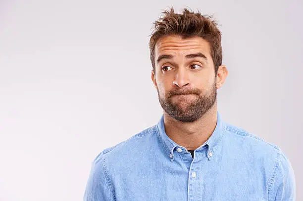 Studio shot of a handsome man looking uncertain against a gray background