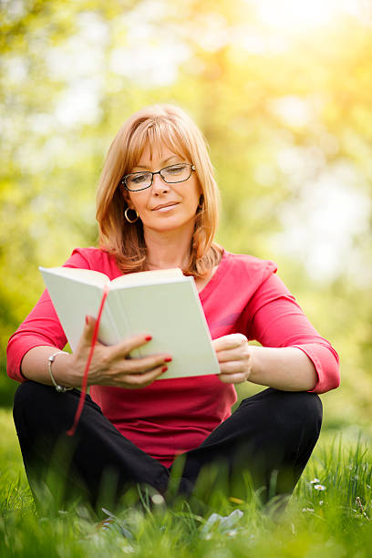 istock Woman reading a book in the park 520002358