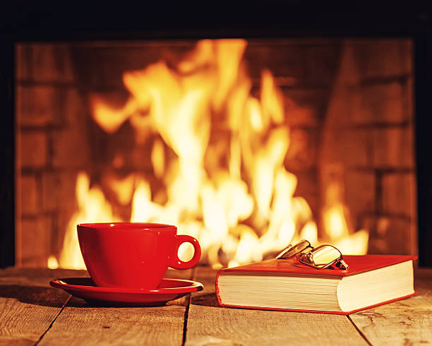 istock Red cup, glasses and old book near fireplace 520002798