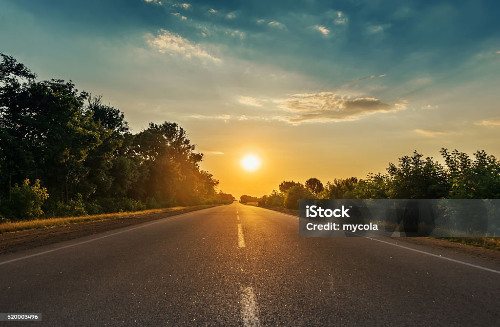 Sol en horizon mientras carretera asfaltada - Foto de stock de Vía libre de derechos