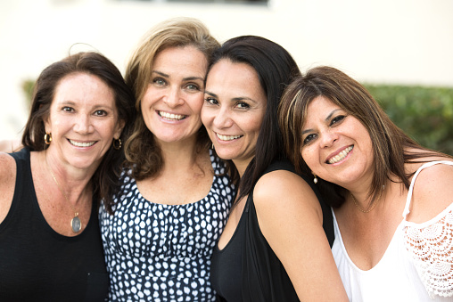 four hispanic or middle eastern mature women posing looking at the camera smiling