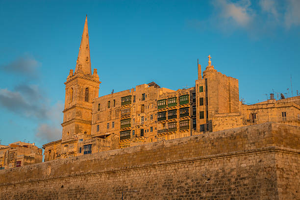 Street view with church spire and traditional residential buildings in  Valletta, Maltese island.