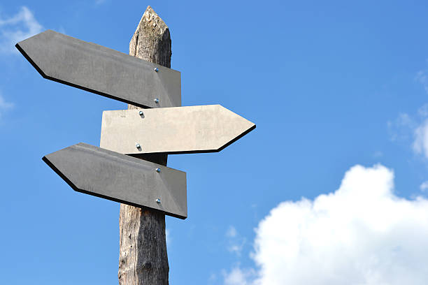 Wooden signpost with 3 arrows Wooden signpost with 3 arrows, blue sky in background. crossroads sign stock pictures, royalty-free photos & images