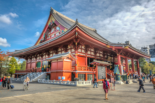 Tokyo, Japan - November 12, 2015:  Asakusa Senso-ji ancient Kannon temple main hall, in Tokyo, Japan. Some tourists are walking around this distinctive red landmark. This is a corner, wide angle photograph of this building. Sensō-ji is an ancient Buddhist temple located in Asakusa, Tokyo, Japan. It is Tokyo's oldest temple, and one of its most significant. 