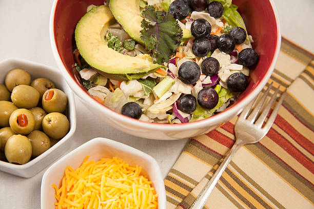 istock Mixed greens salad in bowl. Olives, cheese, fork, napkin. 520007536